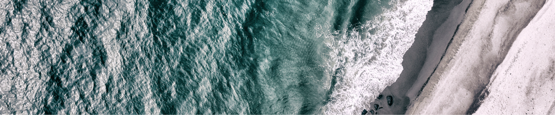 water waves hitting the shore of a beach with grey sand